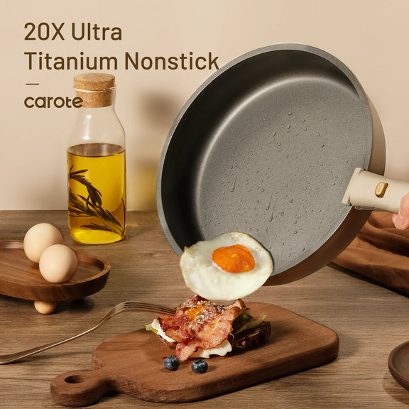 Nonstick frying pan with a fried egg on a wooden cutting board, next to a bottle of oil and eggs.