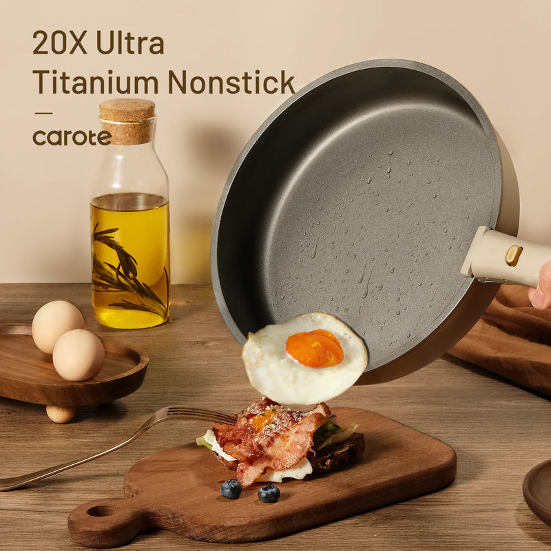 Nonstick frying pan with a fried egg on a wooden cutting board, next to a bottle of oil and eggs.