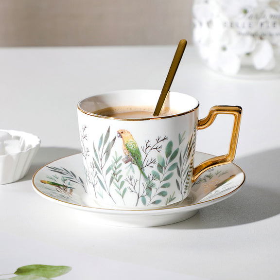 Ceramic cup with saucer featuring a bird design on a white surface.