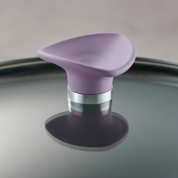 Purple handle on glass lid with metallic base on a reflective surface