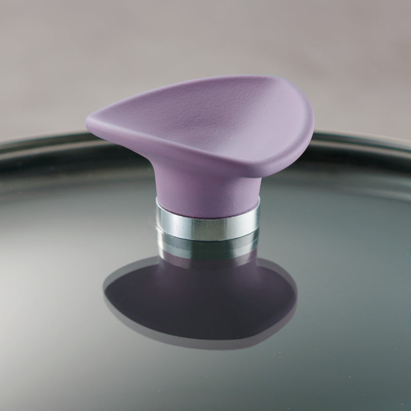 Purple handle on glass lid with metallic base on a reflective surface