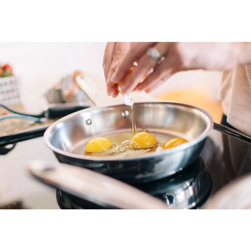 Person cracking eggs in a frying pan