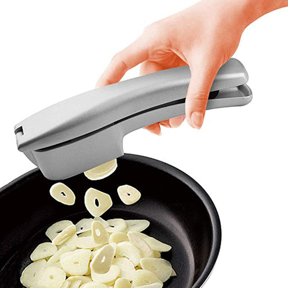 Hand using a garlic press to crush garlic into a pan.