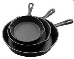 Set of three cast iron skillets of different sizes on a white background