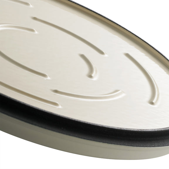 Close-up of a white oval-shaped dutch oven  with black rim on a white background