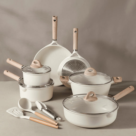 Set of white cookware with wooden handles on a gray surface
