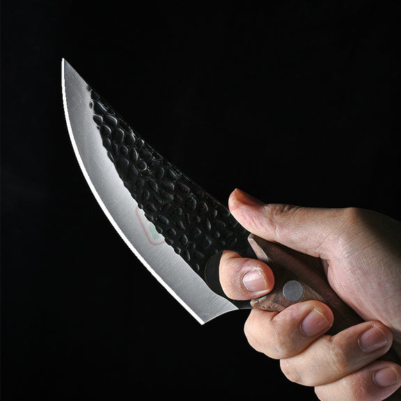 Hand holding a knife with a textured blade against a black background