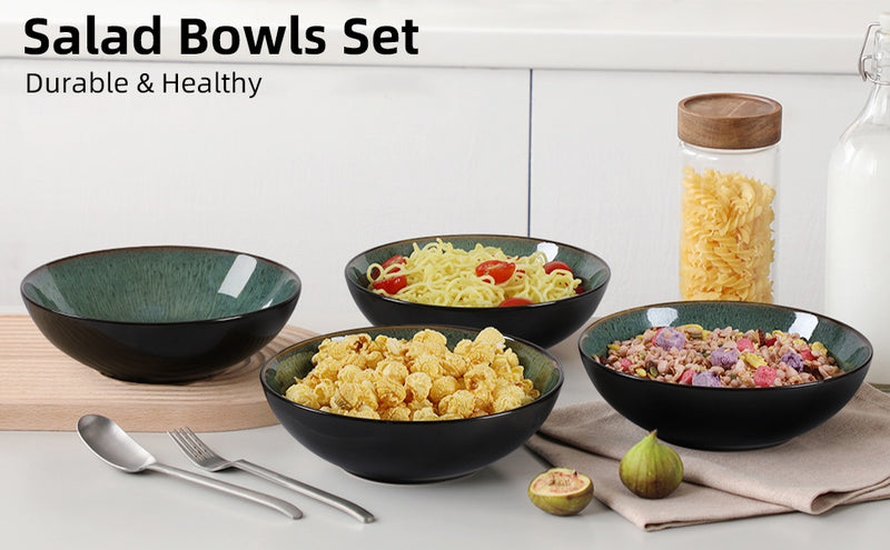 Set of black salad bowls with various contents on a white surface, with a jar of pasta in the background.