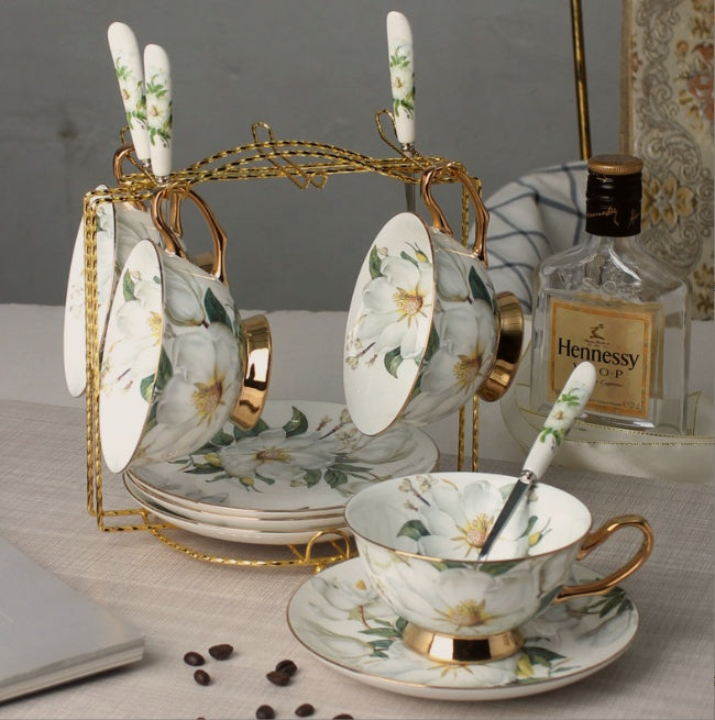 Tea set with floral design on a table next to Hennessy cognac bottle.