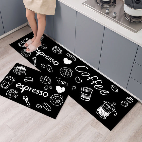 Two black kitchen mats with white coffee-themed designs on a wooden floor.