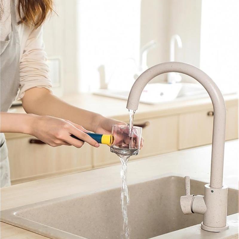 Person using a water filter on a glass in a kitchen with a modern faucet.