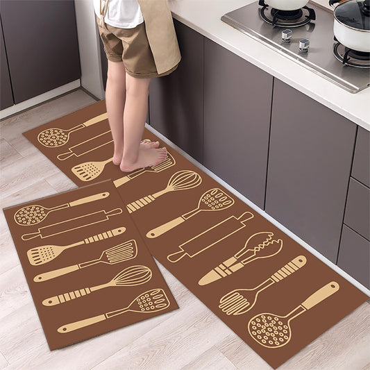 Brown kitchen mats with utensil patterns on a wooden floor in a kitchen.