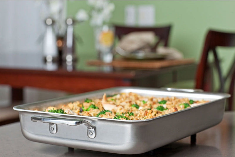 Stainless steel baking dish with food on a table in a home setting
