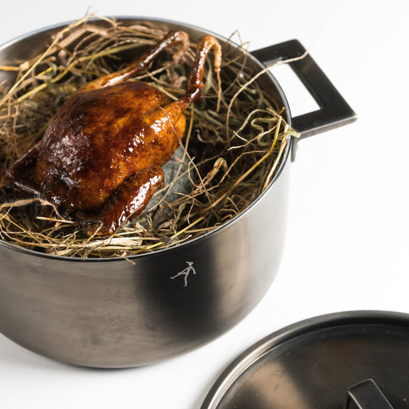 Roasted duck in a metal pot on a white background