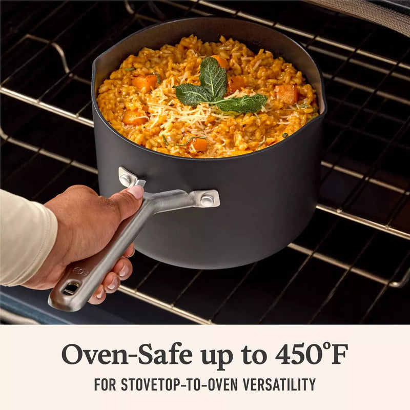 Black pot with food being held above an oven, text indicating oven-safe temperature.