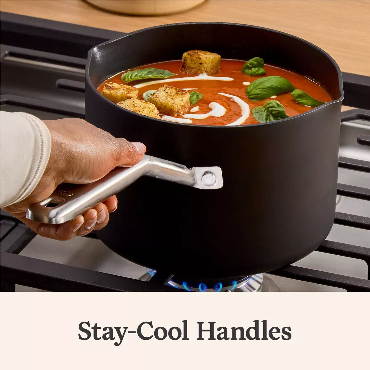 Black pot with tomato soup on a stove, featuring 'Stay-Cool Handles' text.