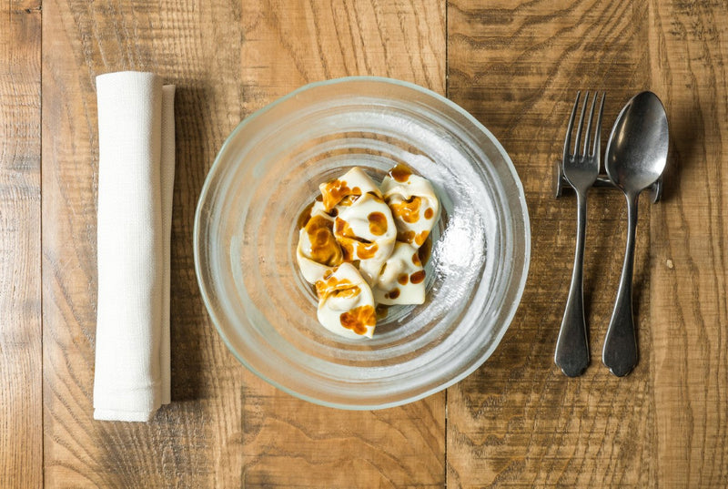 Glass bowl with food on a wooden table with cutlery