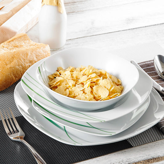 White ceramic bowl with cereal on a white plate with green stripes, on a wooden table.