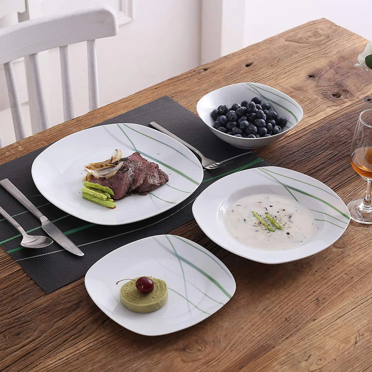 Dinner setting with plates, bowls, and cutlery on a wooden table.