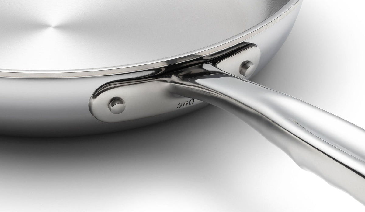 Close-up of a stainless steel frying pan with a visible brand logo on a light gray background
