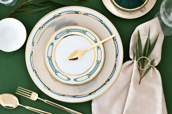 Elegant dinnerware set with gold accents on a green tablecloth