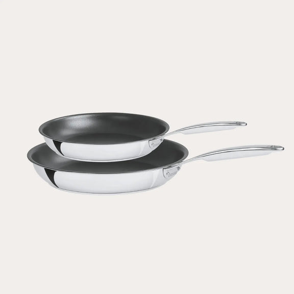 Two frying pans with silver handles on a light gray background