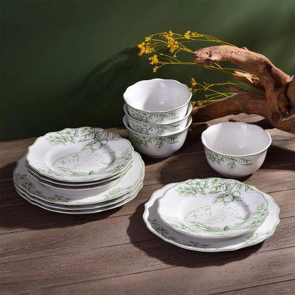 Set of white ceramic dishes with green patterns on a wooden surface.