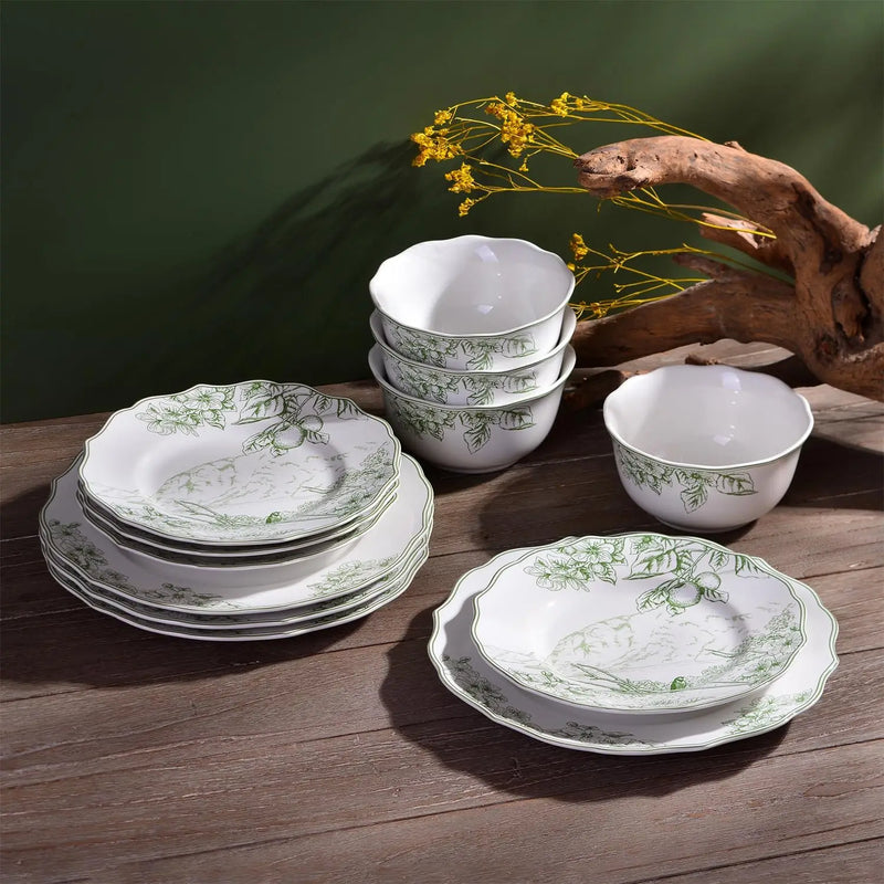 Set of white ceramic dishes with green patterns on a wooden surface.