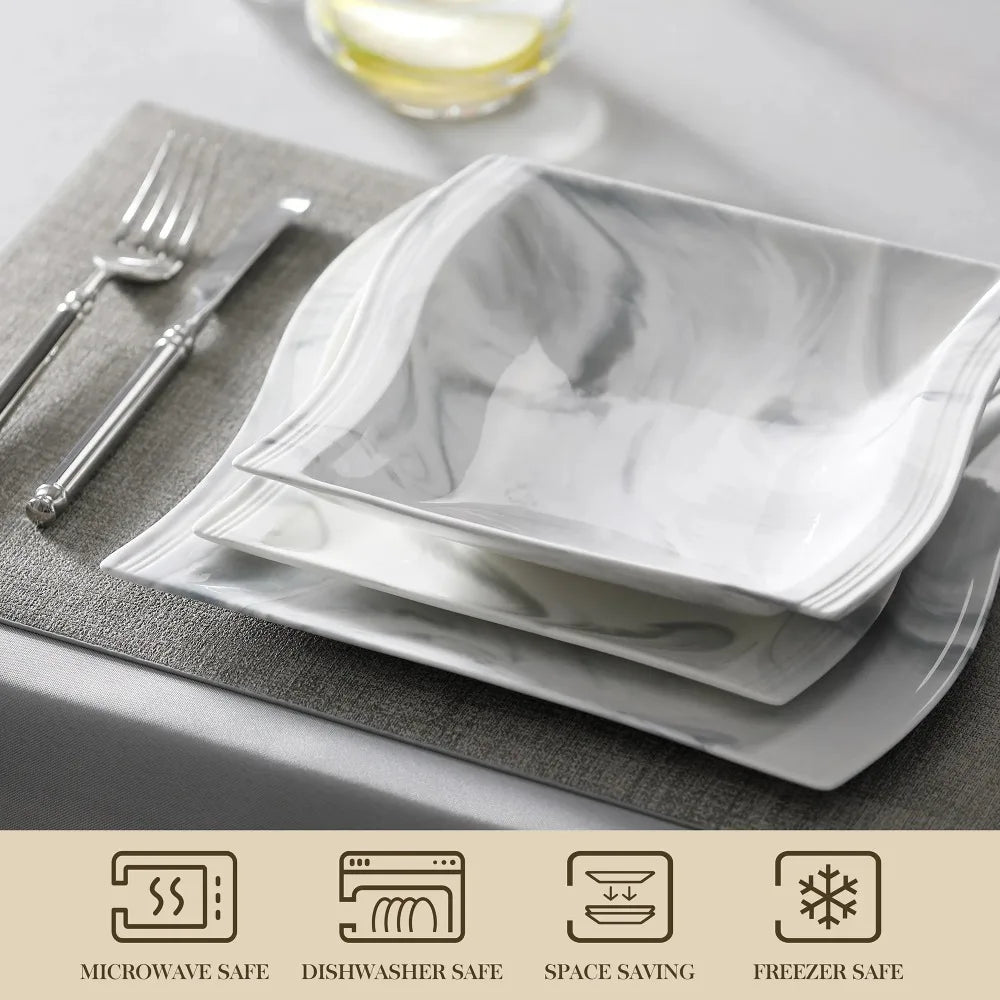 Set of white square plates on a gray placemat with cutlery and glass.