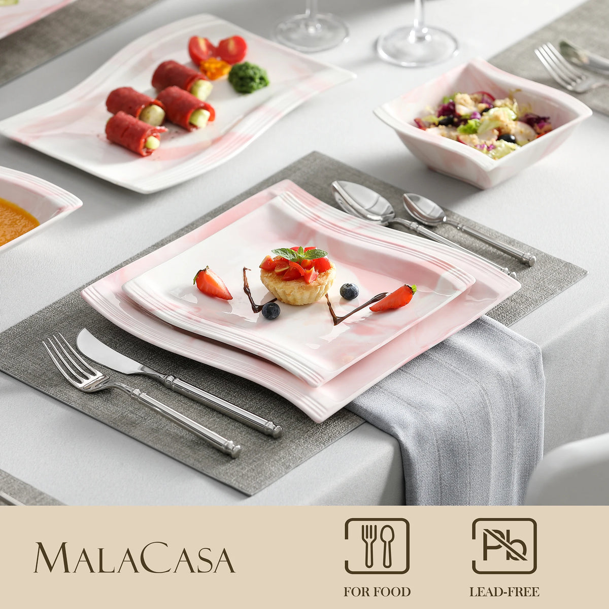 Dining table setting with Malacasa plates, cutlery, and food on a gray tablecloth.