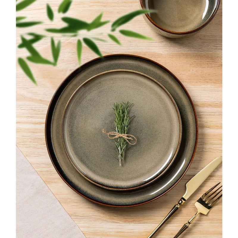 Set of ceramic plates with a sprig of rosemary on a wooden table.