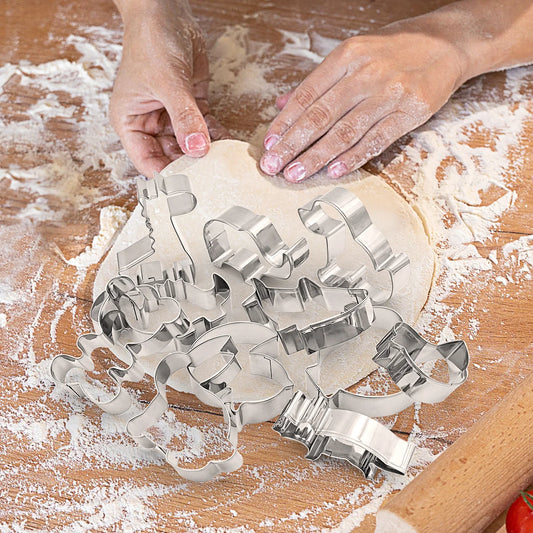 Person using cookie cutters on rolled-out dough with flour on a wooden surface