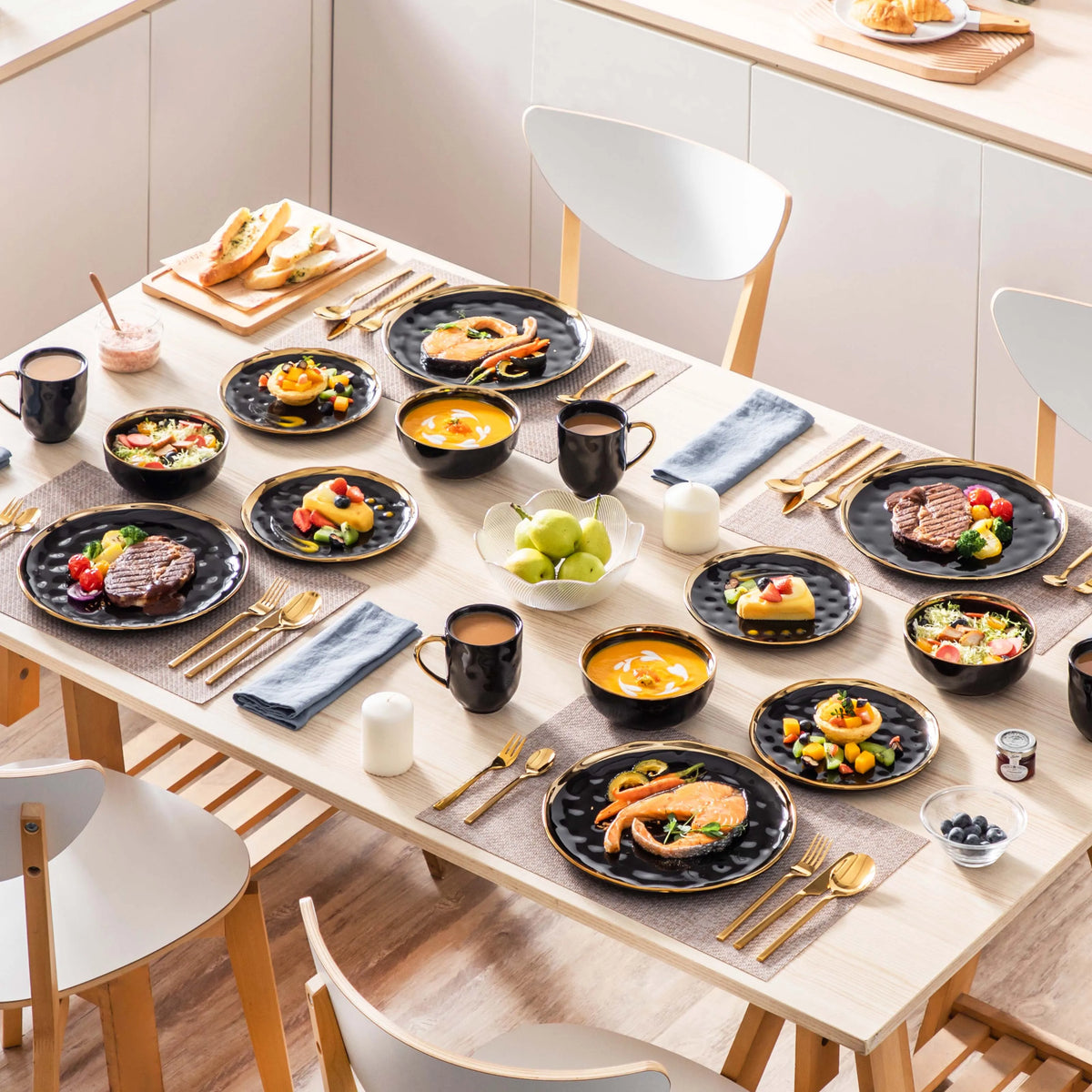 Dining table set with plates of food and coffee cups on a light-colored wooden floor.