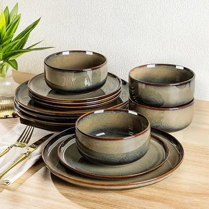 Set of ceramic bowls and plates on a wooden table with a plant in the background