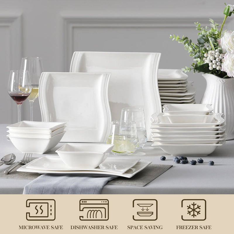 White ceramic dinnerware set on a table with decorative elements.
