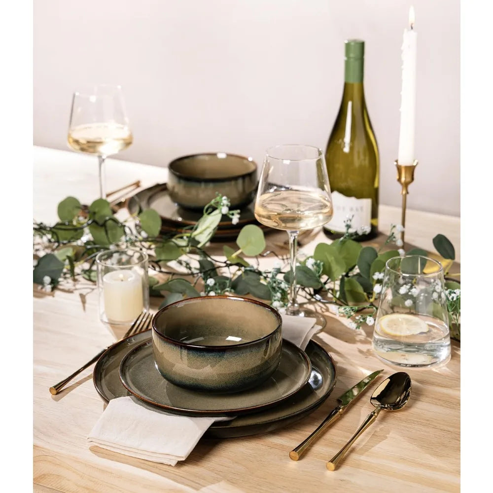Elegant dinner table setting with greenery, wine, and cutlery on a wooden table.