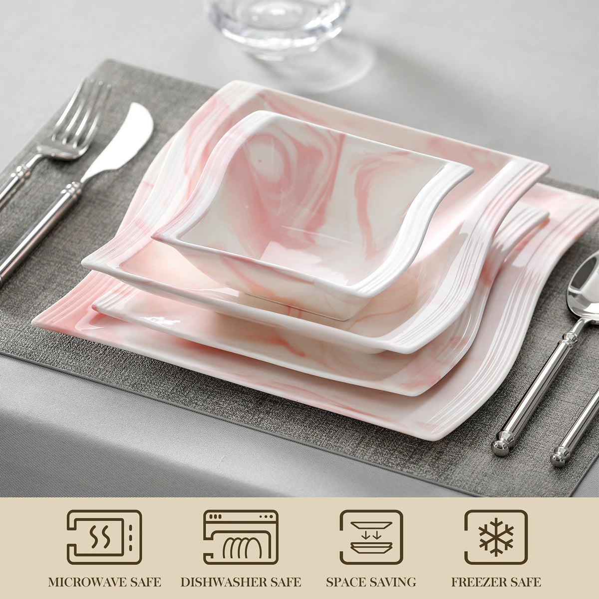 Set of pink and white marbled ceramic plates on a gray placemat with silverware.