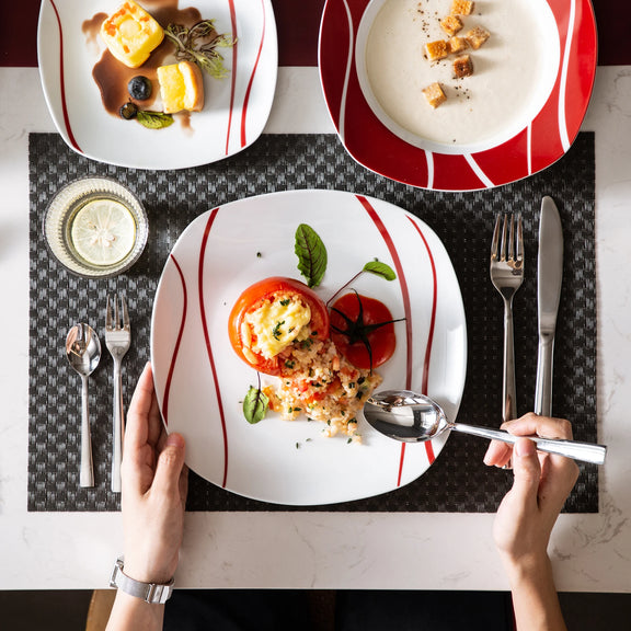 Dinner setting with plates of food, cutlery, and a glass on a checkered tablecloth.