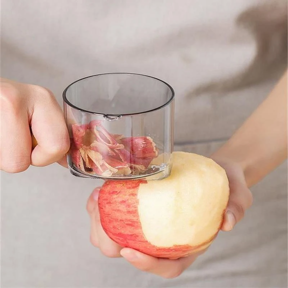 Clear glass cup being used to scoop out the inside of a red apple.