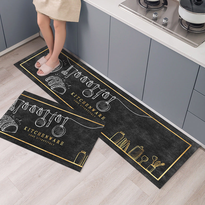 Two black kitchen mats with white and gold designs on a wooden floor.