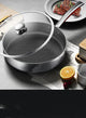 Stainless steel cookware set on a table with food and an orange.
