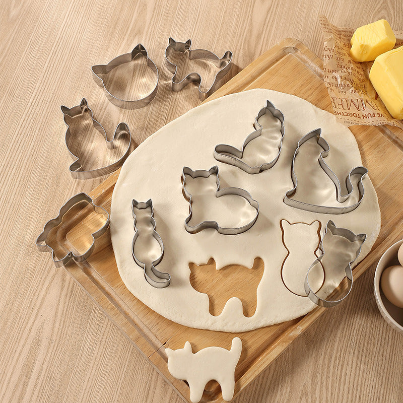 Cat-shaped cookie cutters on a wooden board with dough