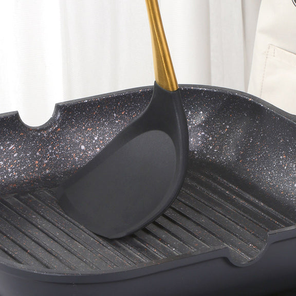 Black speckled grill pan with a black spatula on a white background