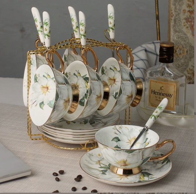 Tea set with floral design on a table with Hennessy bottle in the background