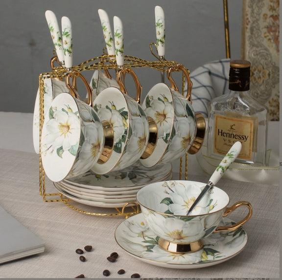 Tea set with floral design on a table with Hennessy bottle in the background
