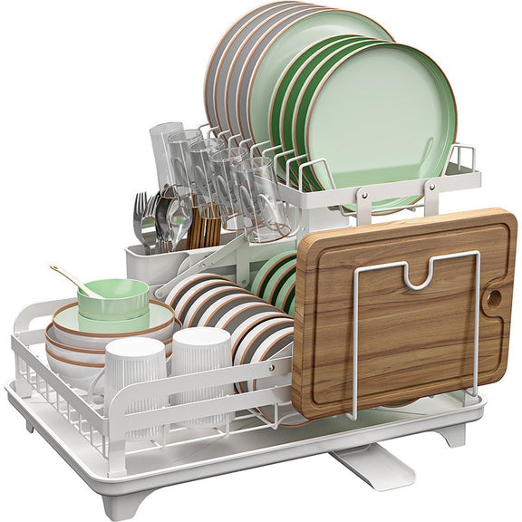 Dish drying rack with green plates, cups, glasses, and a wooden cutting board on a white background