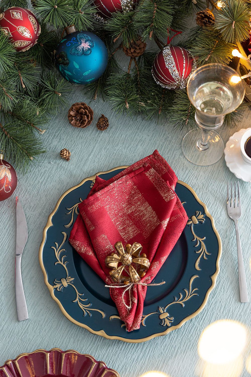 Decorative Christmas table setting with greenery, ornaments, and a red napkin.