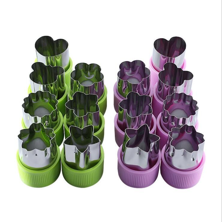 Set of metal cookie cutters in green and pink containers on a white background