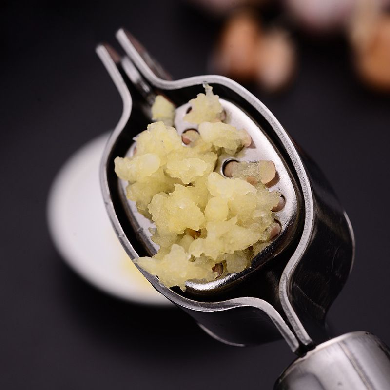 Garlic press with minced garlic on a dark background