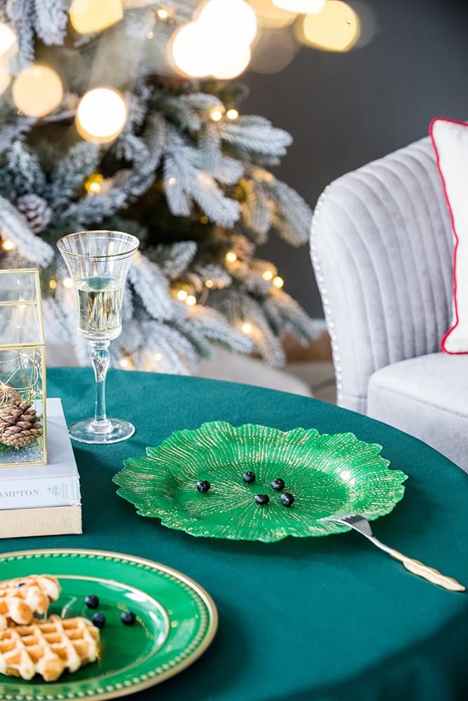 Green table setting with a Christmas tree in the background
